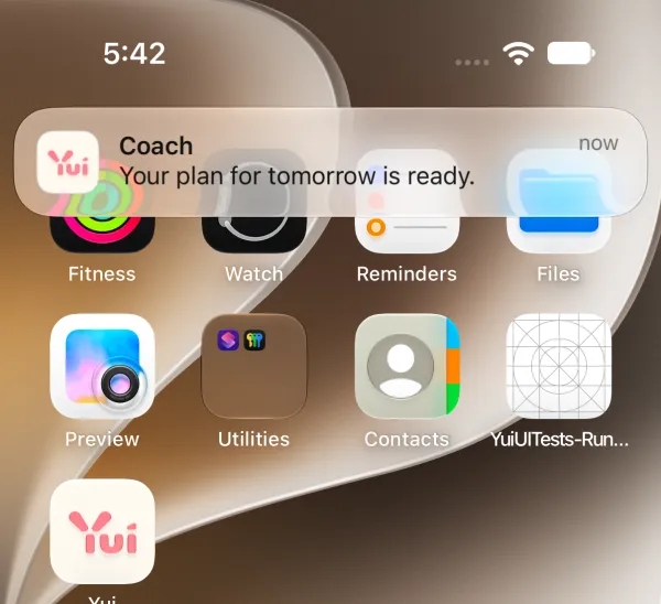 iPhone home screen with a Yui notification from Coach: Your plan for tomorrow is ready.